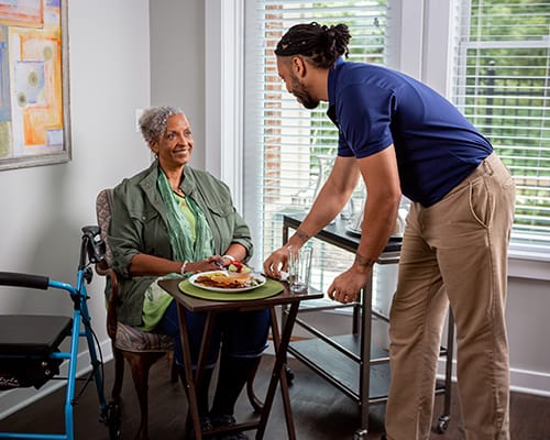 caregiver hanging a painting for a resident
