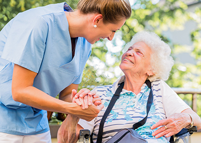 Caregiver holding older woman's hand