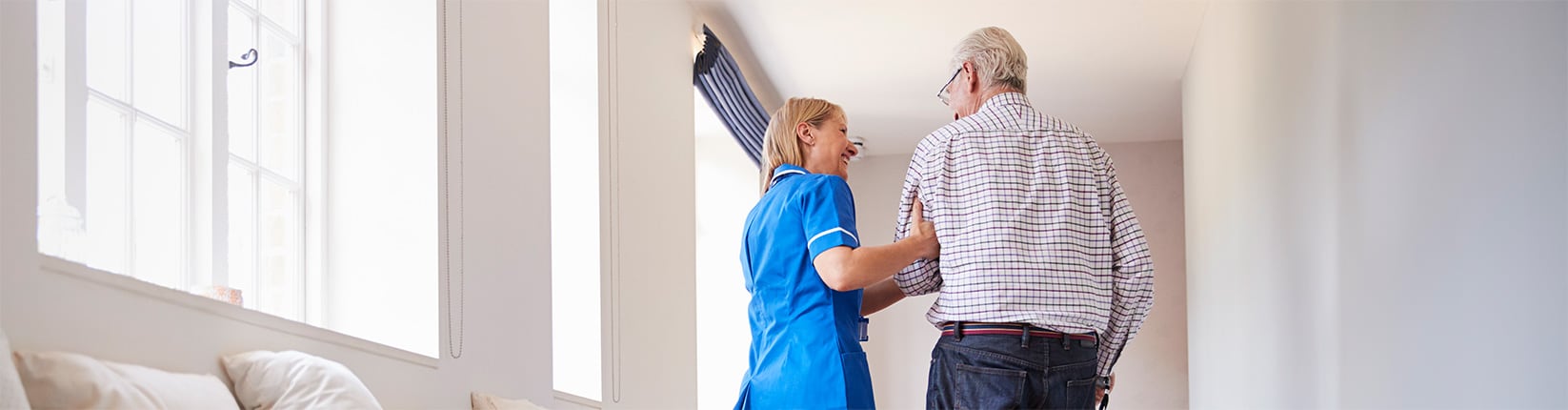 caregiver helping man walk with cane