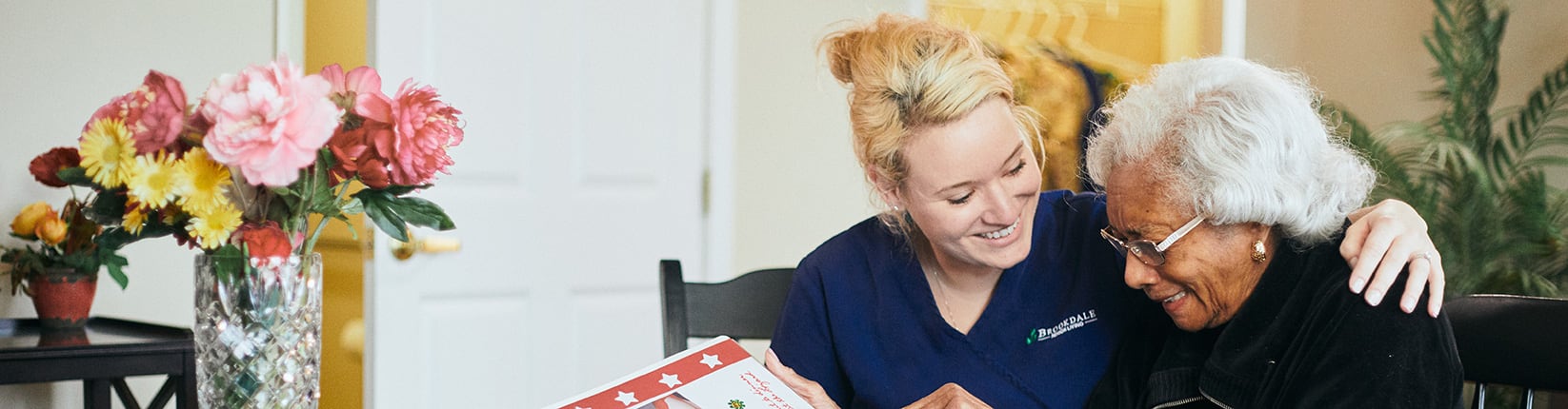 caregiver and woman looking at a scrapbook