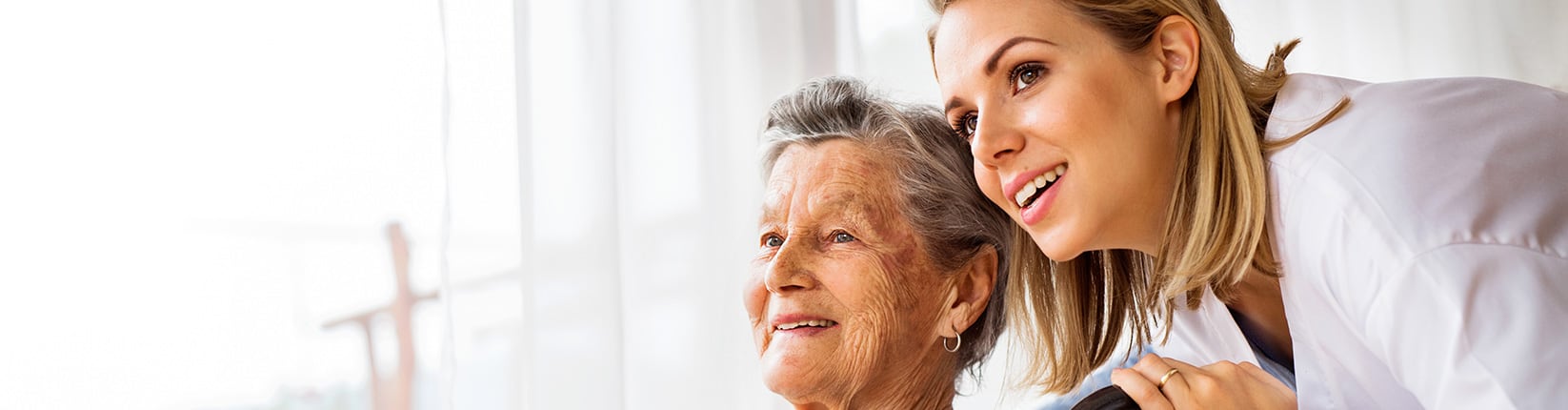 caregiver and women in wheelchair looking outside