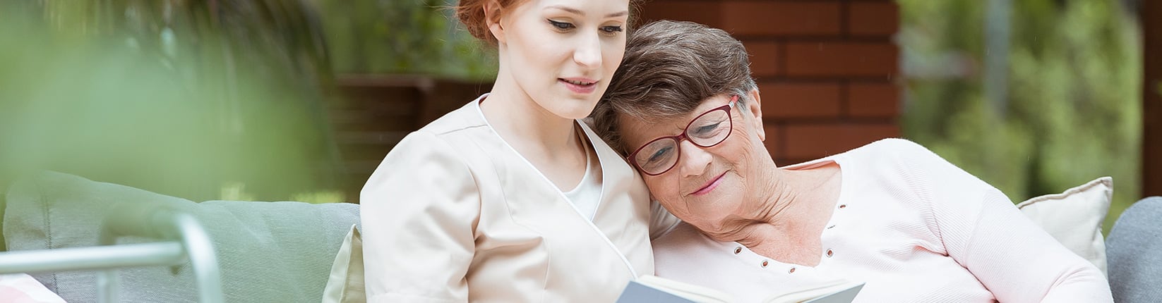 nurse reading to elderly woman