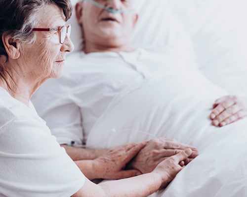 wife with husband in hospital bed