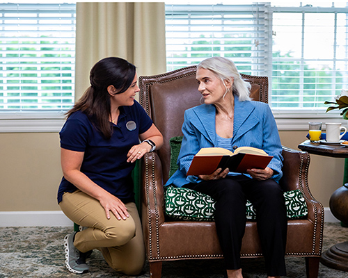 caregiver helping resident put on a necklace