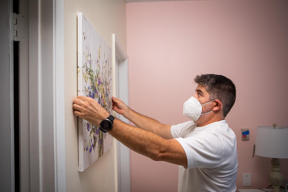  Design team member hangs a painting on the wall
