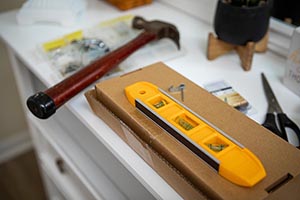  A level, hammer, and other tools for hanging things on walls sitting on a dresser